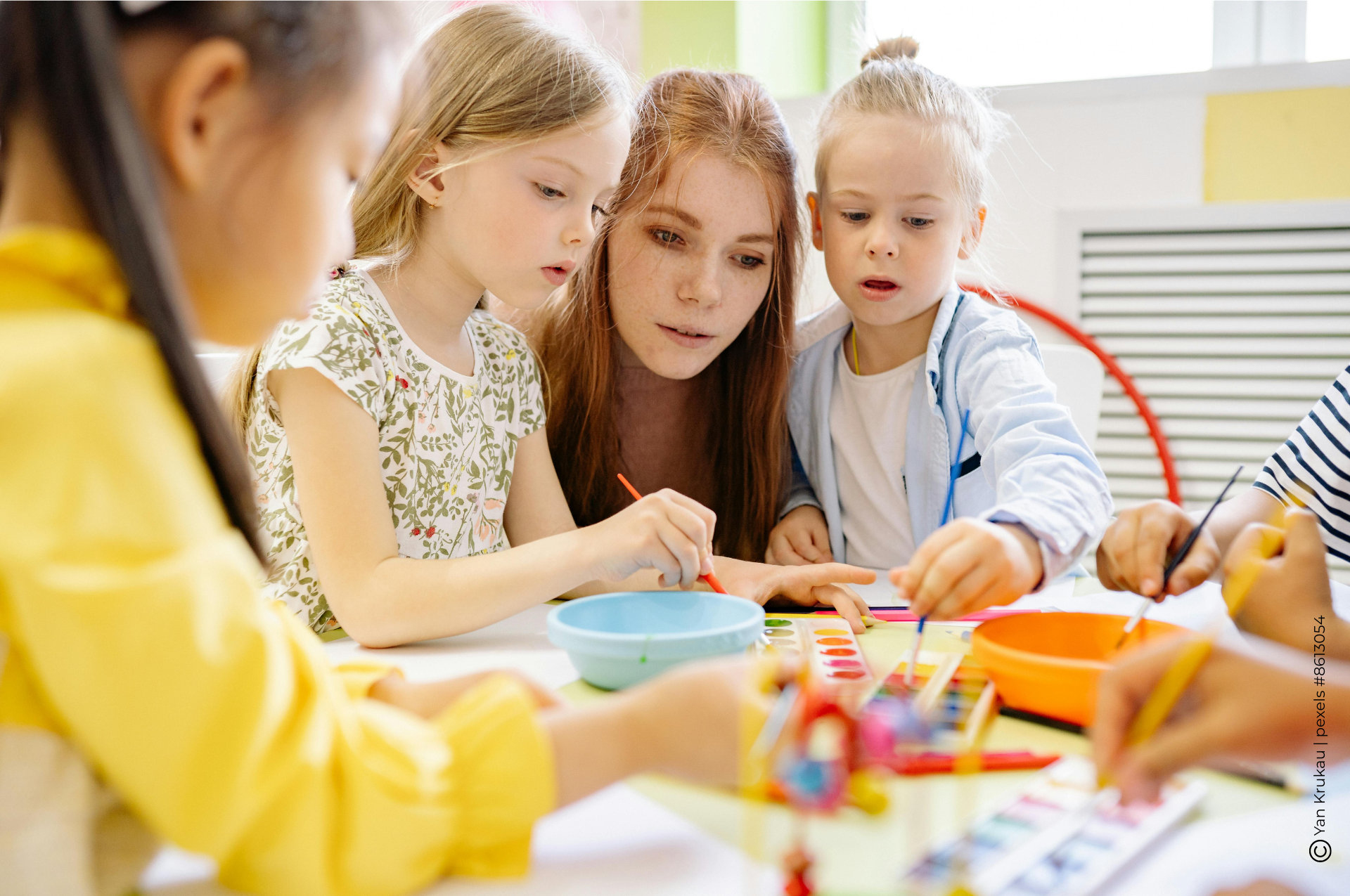 Erzieherin malt mit 3 Kindern